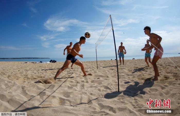 资料图：当地时间5月25日，民众在西班牙大加那利岛重新开放的海滩上玩乐休闲。图为民众在沙滩上玩网式足球。